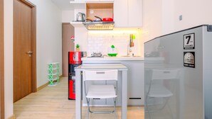 Een compacte keuken met witte kasten, een klein eiland, een koelkast en een magnetron.