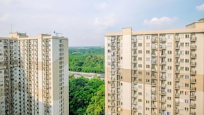 Een hoog appartementencomplex met meerdere balkons en uitzicht op een groen landschap.
