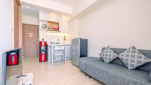 Een moderne woonkamer met een grijze bank, twee gestreepte kussens, een flatscreen televisie en een koffiezetapparaat.