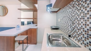 A modern kitchen with wooden cabinets, a white countertop, a stainless steel sink, and a tiled backsplash.