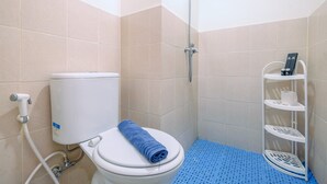 Une salle de bain avec des toilettes, une douche et une étagère blanche où sont rangés les articles de toilette.