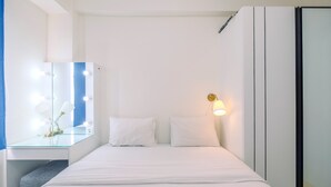 Une chambre d’hôtel comprenant un lit, une coiffeuse avec un miroir et des lampes, et une lampe fixée au mur.