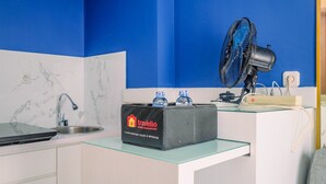 Une cuisine avec un dosseret en marbre, un évier, un ordinateur portable, un sac noir portant l’inscription « Travelio » et un ventilateur bleu.