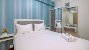 A hotel room with a bed, a nightstand, a mirror, and a wall-mounted air conditioner. - Minimalist and Cozy Stay 2BR at Podomoro Golf View Apartment (Gunung Putri)