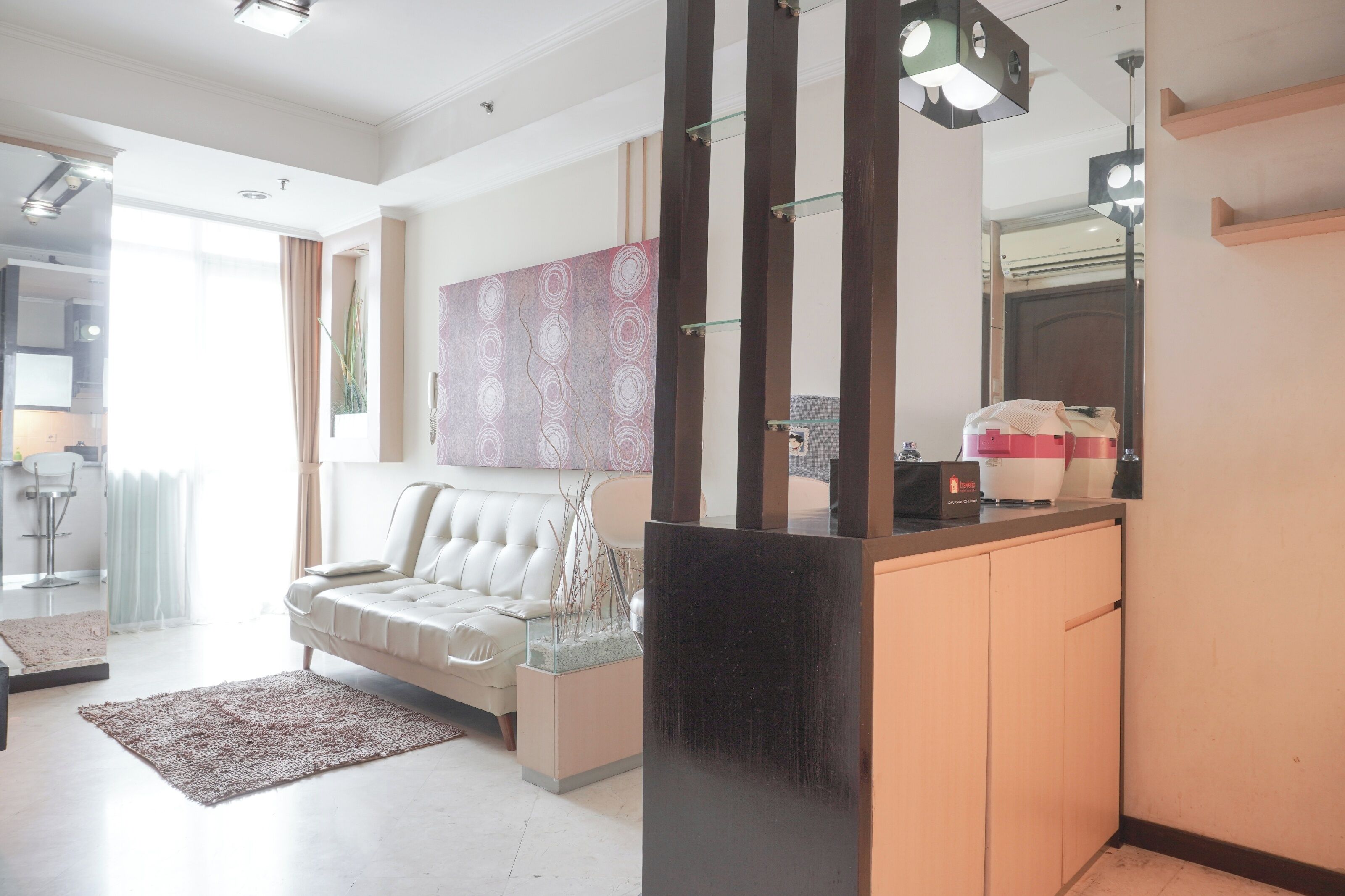 A modern living room with a white sofa, a glass coffee table, and a decorative wall piece.