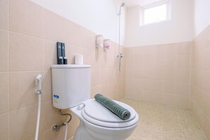 a bathroom with a toilet, water heater, and a window.