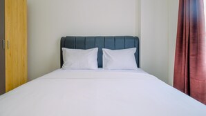 A bed with a dark headboard, white bedding, and a wooden wardrobe to the left. - Comfort Stay 2BR at Podomoro Golf View Apartment (Gunung Putri)