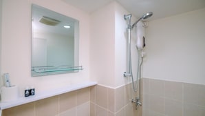 A bathroom with a shower, a mirror, and a shelf with toiletries. - Simply Look and Tidy 2BR at Podomoro Golf View Apartment (Gunung Putri)