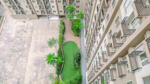 A high-rise residential building with multiple balconies, a central courtyard with greenery, and a parking area. - Simply Look and Tidy 2BR at Podomoro Golf View Apartment (Gunung Putri)