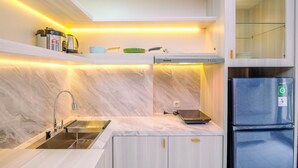 A modern kitchen with a built-in sink, stainless steel appliances, and under-cabinet lighting. - Simply Look and Tidy 2BR at Podomoro Golf View Apartment (Gunung Putri)
