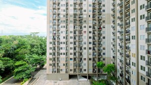 A high-rise residential building with multiple balconies and a green surrounding. - Comfort and Restful 2BR Podomoro Golf View Apartment (Gunung Putri)