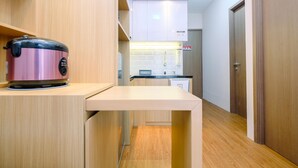 A compact kitchen with a built-in stove, a countertop, and a wooden floor. - Comfort and Restful 2BR Podomoro Golf View Apartment (Gunung Putri)