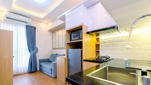 A compact kitchen with a black countertop, stainless steel sink, and a microwave. - Comfort and Restful 2BR Podomoro Golf View Apartment (Gunung Putri)