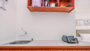A modern kitchen with a stainless steel sink, a built-in oven, and a wooden countertop. - Comfortable and Lovely Studio Podomoro Golf View Apartment (Gunung Putri)