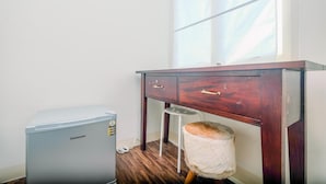 A room with a wooden desk, a small stool, and a Changhong refrigerator. - Comfortable and Lovely Studio Podomoro Golf View Apartment (Gunung Putri)