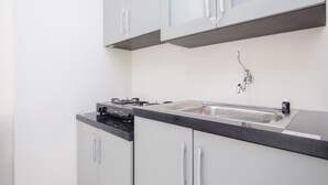 A modern kitchen with white cabinets, a black countertop, and stainless steel appliances. - Comfort 2BR at 6th Floor Podomoro Golf View Apartment (Gunung Putri)