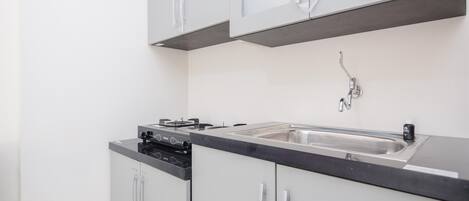 A modern kitchen with white cabinets, a black countertop, and stainless steel appliances.