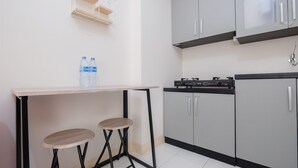 A kitchen with a countertop, two stools, and cabinets. - Comfort 2BR at 6th Floor Podomoro Golf View Apartment (Gunung Putri)