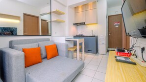 A modern living room with a grey sofa and orange cushions, a wooden coffee table, and a TV. - Best Deal and and Cozy 2BR Podomoro Golf View Apartment (Gunung Putri)