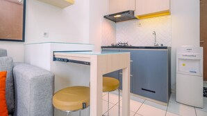 A compact kitchen with a built-in stove, a sink, and a refrigerator. - Best Deal and and Cozy 2BR Podomoro Golf View Apartment (Gunung Putri)