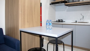 A compact kitchen with a white countertop, a sink, and a wooden cabinet. There are two bottles of water on the countertop. - Comfort 2BR at 28th Floor Podomoro Golf View Apartment (Gunung Putri)