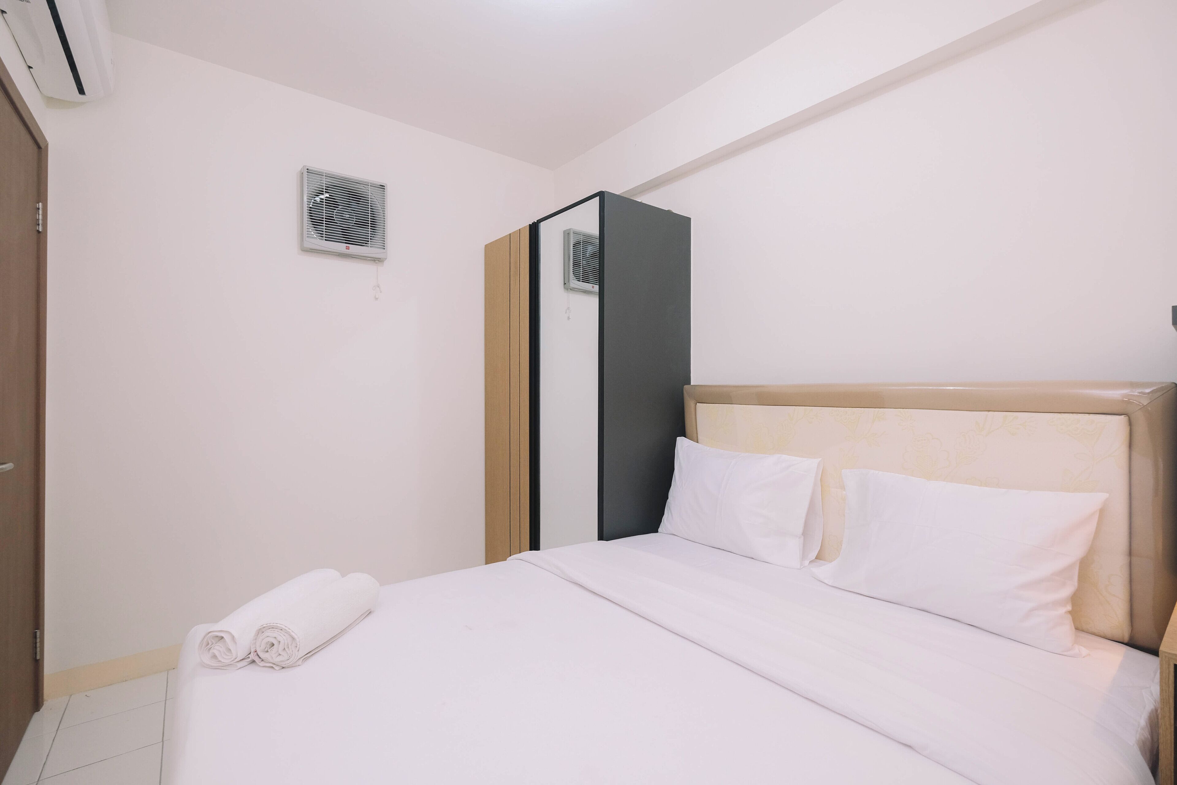 A hotel room with a bed, a wardrobe, and an air conditioning unit.
