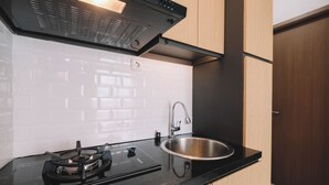 A modern kitchen with a black countertop, stainless steel sink, and a gas stove. - Simple and Cozy Living 2BR at Podomoro Golf View Apartment (Gunung Putri)
