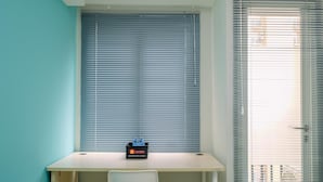 A room with a desk, a chair, and a window with blinds. - Contemporary Studio at Podomoro Golf View Apartment (Gunung Putri)