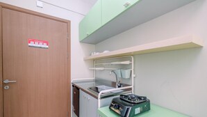 A compact kitchen with a sink, a stove, and a cabinet above the counter. - Contemporary Studio at Podomoro Golf View Apartment (Gunung Putri)
