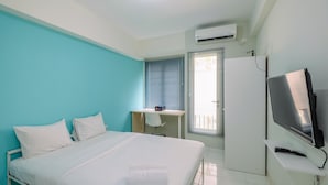 A hotel room with a bed, a desk, a TV, and an air conditioning unit. - Contemporary Studio at Podomoro Golf View Apartment (Gunung Putri)