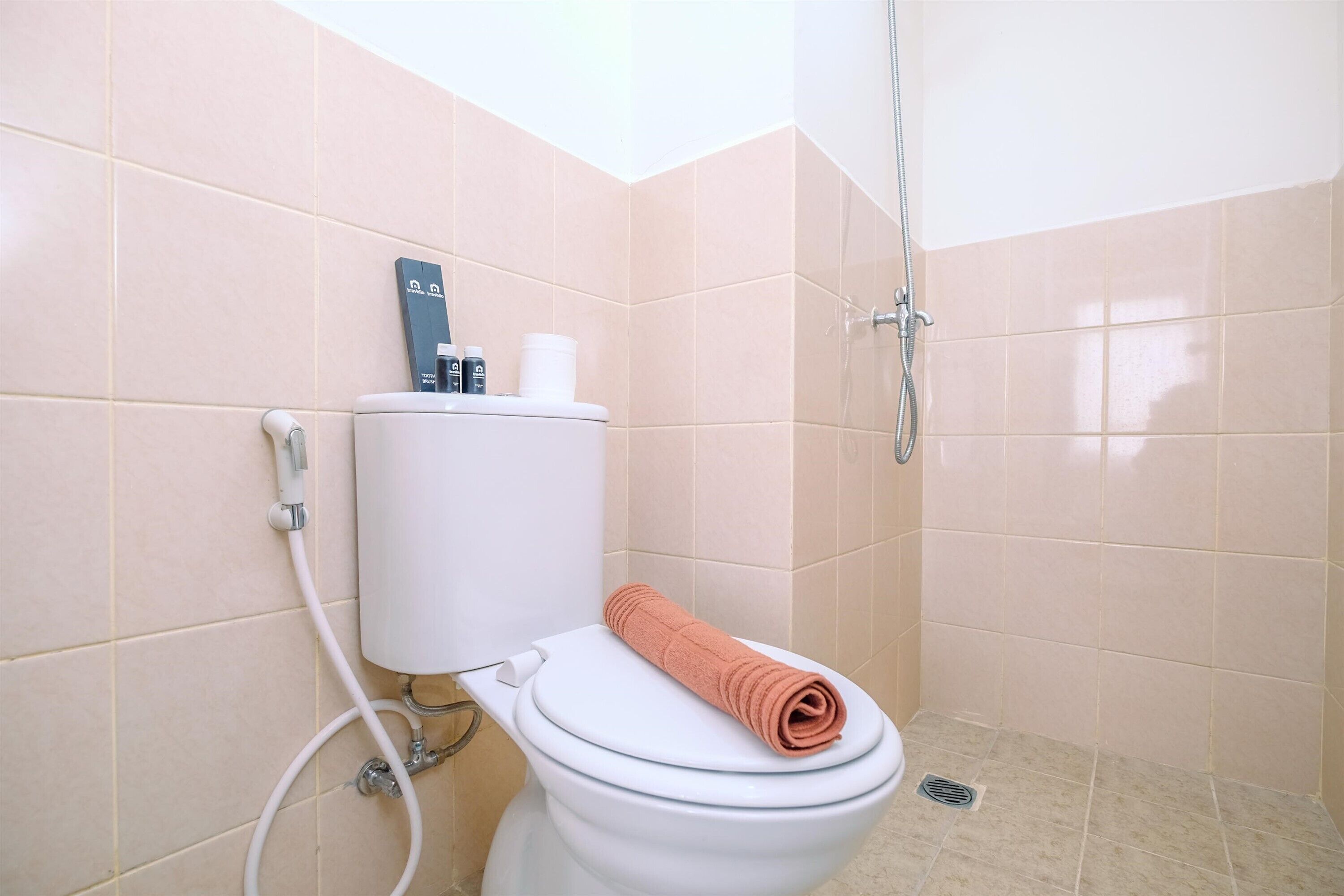 A bathroom with a toilet, a shower, and a towel on the seat.