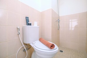 Un baño con inodoro, ducha y una toalla sobre el asiento.