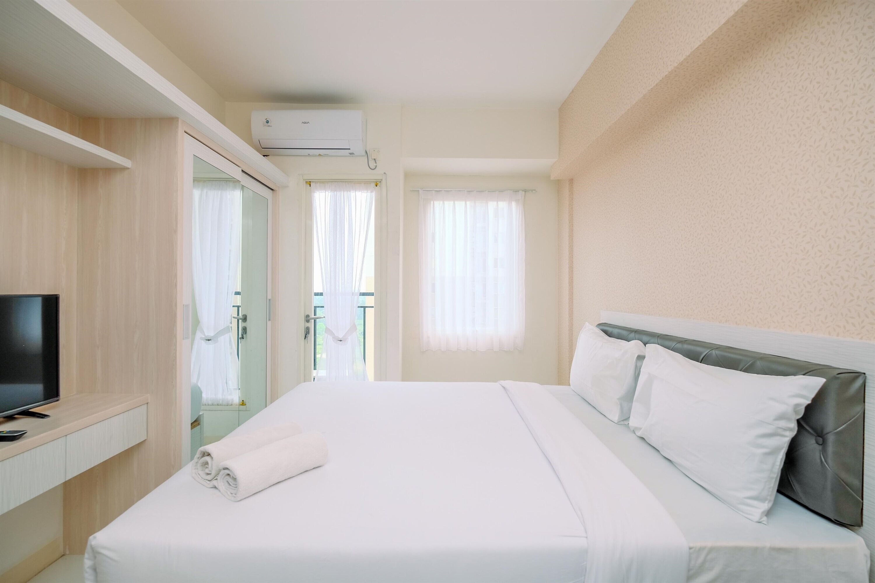 Ein Hotelzimmer mit Bett, Fernseher und Schreibtisch.
