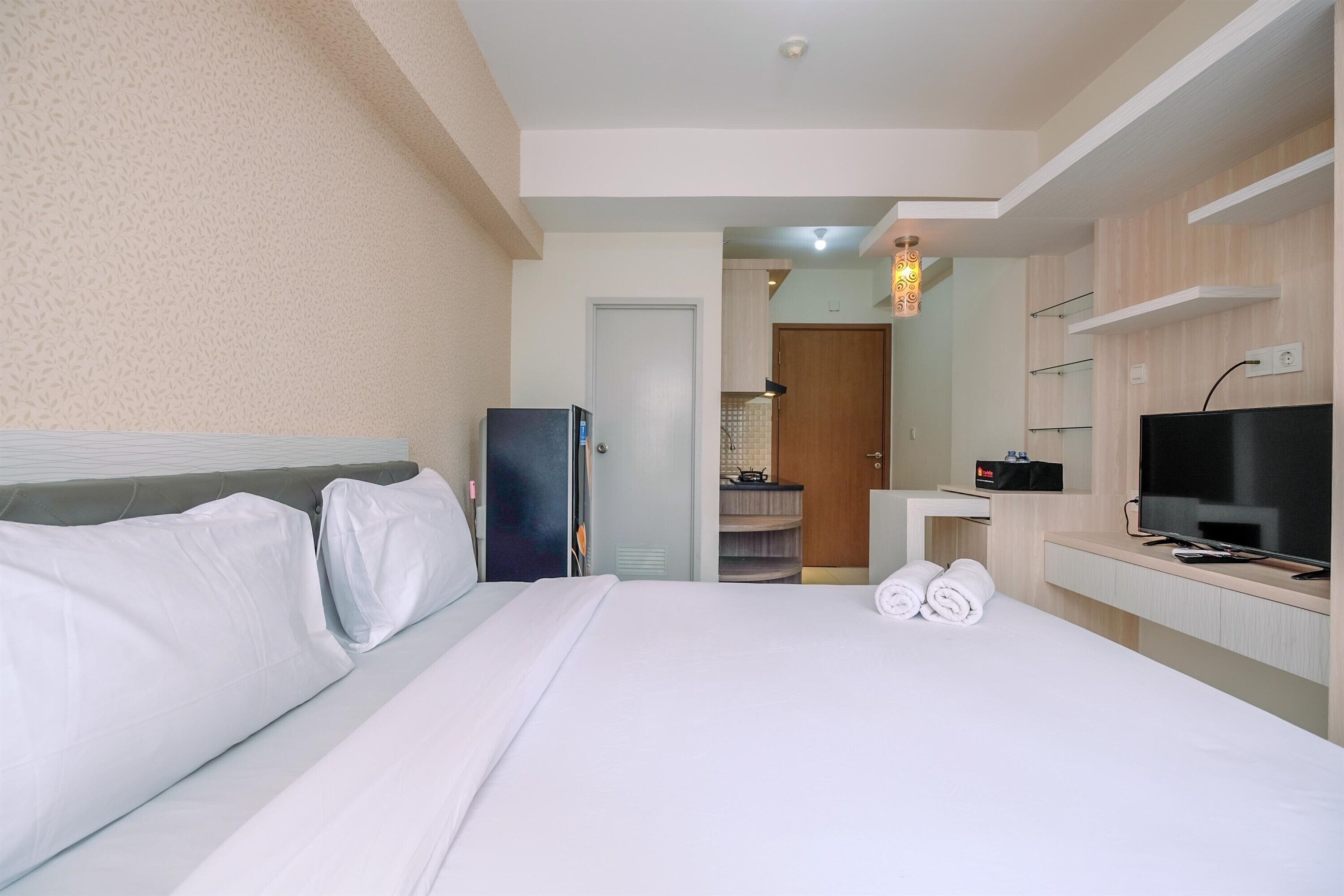 A hotel room with a bed, a television, a desk, and a bathroom visible through an open door.