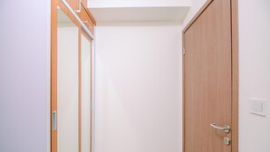 Una stanza con una porta di legno, una porta scorrevole in vetro e un interruttore sulla parete.