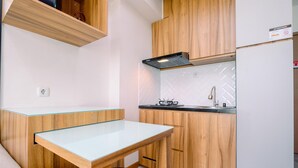 Une cuisine compacte avec des meubles en bois, une table à plateau en verre et une cuisinière encastrée.