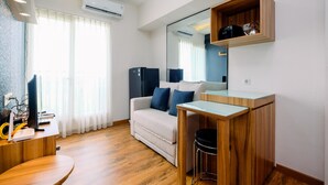 Une pièce moderne avec un bureau en bois, un canapé, une table en verre et un miroir.