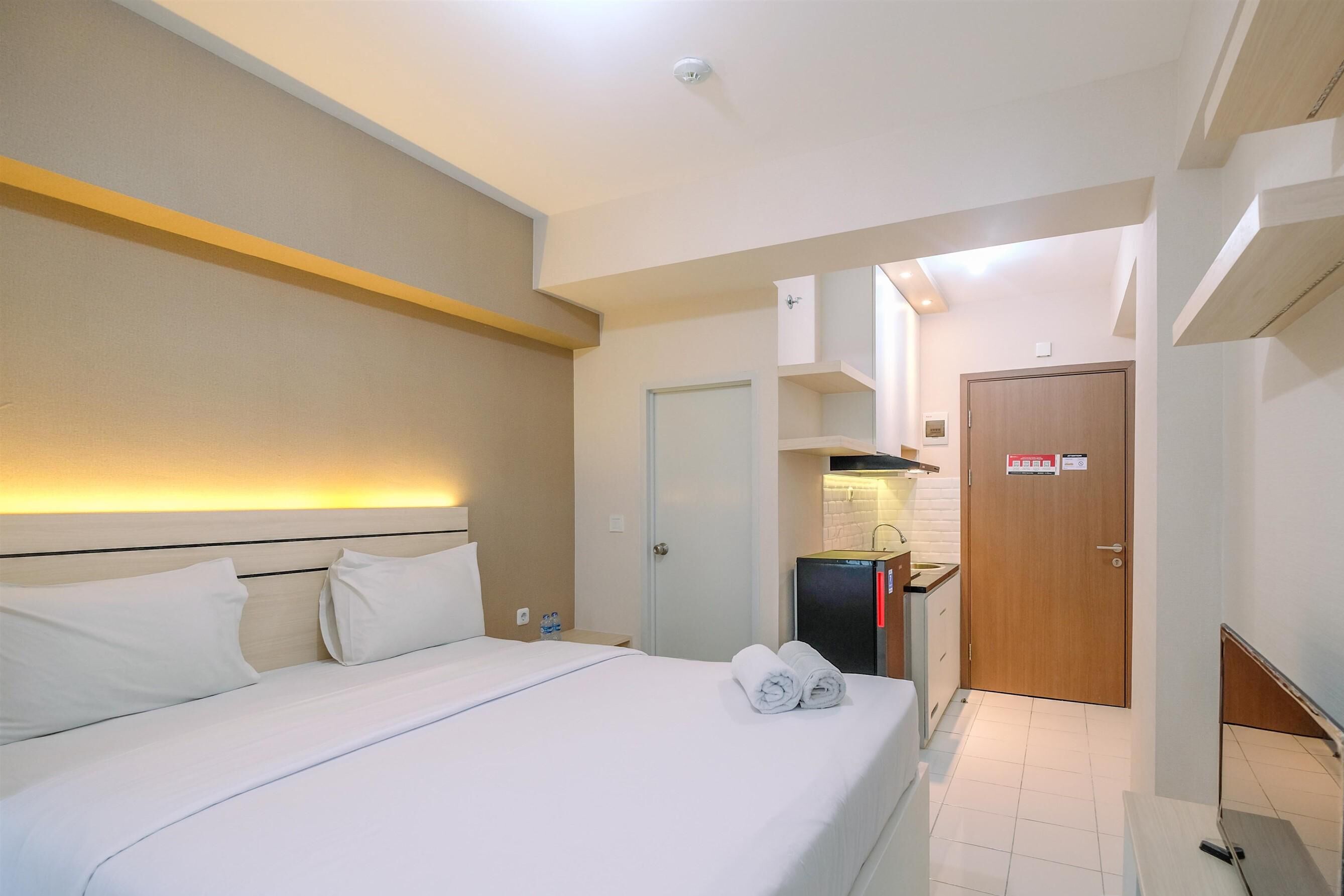 Una habitación de hotel con una cama, un pequeño rincón americano y una puerta que da a otra habitación.