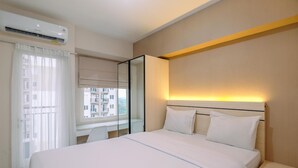 Ein Hotelzimmer mit Bett, Schreibtisch, Stuhl, Nachttisch und einem Fenster mit Vorhängen.