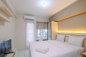 Una habitación de hotel con cama, televisión, aire acondicionado y ventana con cortinas.