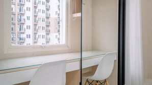 Ein modernes Zimmer mit einem Glastisch, weißen Stühlen, einem großen Fenster mit Blick auf ein Wohngebäude und einem schwarzen Vorhang.