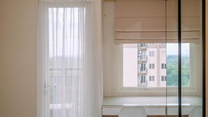 Ein Zimmer mit großem Fenster, einem Vorhang, einem Deckenventilator und Blick auf ein Gebäude.