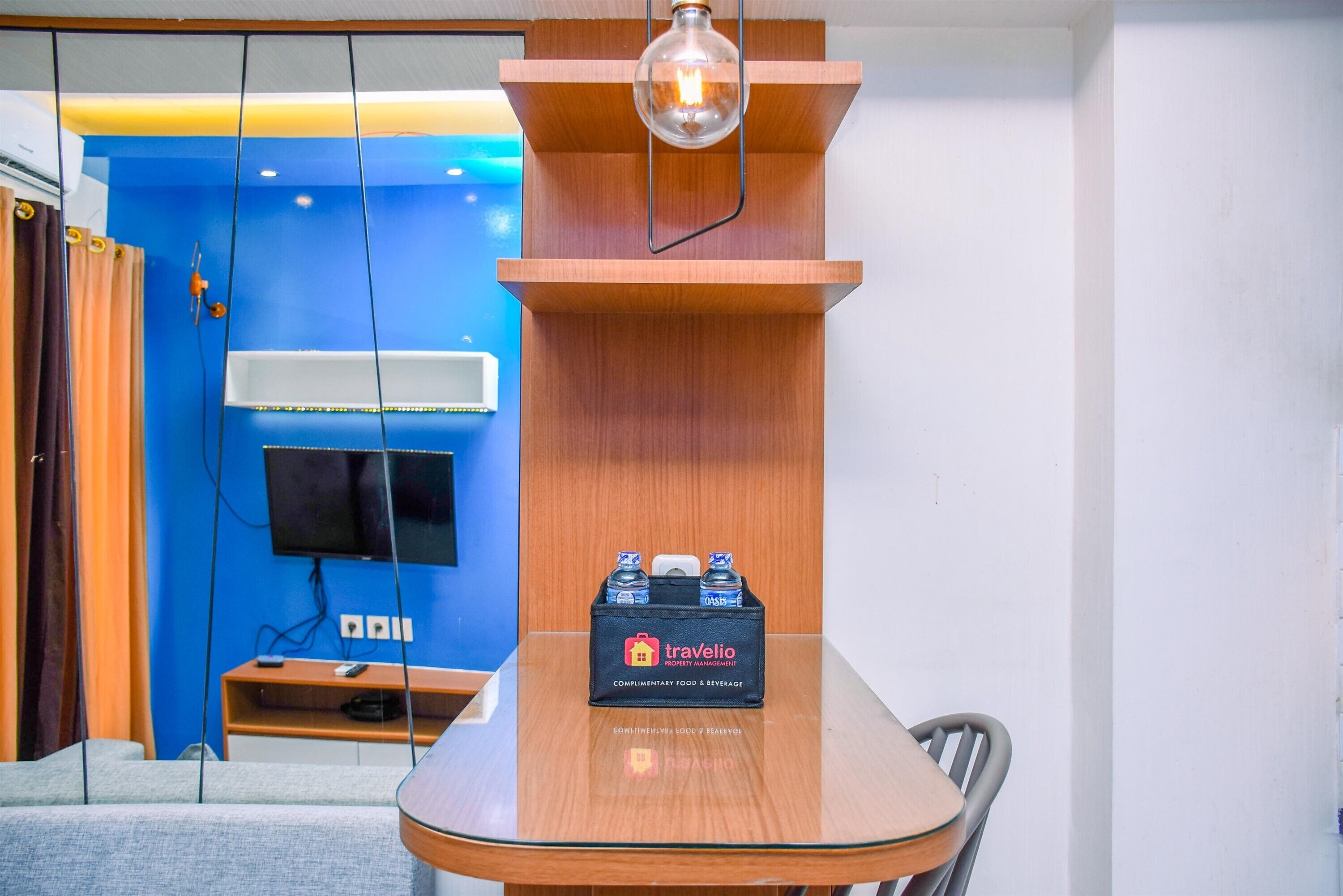 Una habitación de hotel moderna con una mesa de comedor de madera, un minibar y un televisor montado.