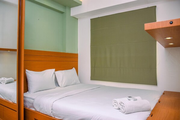 Restful retreat with a neatly made bed, wooden headboard, and a lamp on a nightstand.