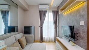 Een moderne woonkamer met een bank, televisie en een airconditioner.