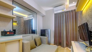 Een moderne hotelkamer met een bank, een flatscreen televisie, een minibar en een grote spiegel.