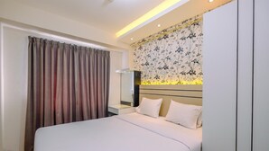 Een hotelkamer met een groot bed, een nachtkastje, een spiegel en een wand met bloemenbehang.