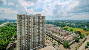 Een hoog appartementencomplex met meerdere verdiepingen en balkons, omgeven door groen en andere woongebouwen.