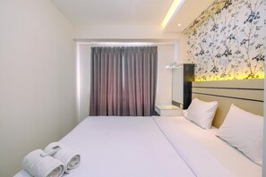 A hotel room with a neatly made bed, a bedside table with a lamp, and a window with curtains. - Nice and Comfortable 2BR at Podomoro Golf View Apartment (Gunung Putri)
