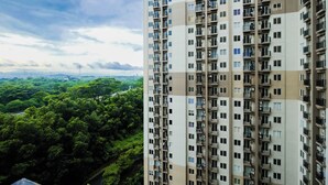 A high-rise building with multiple balconies and a view of a lush green landscape.